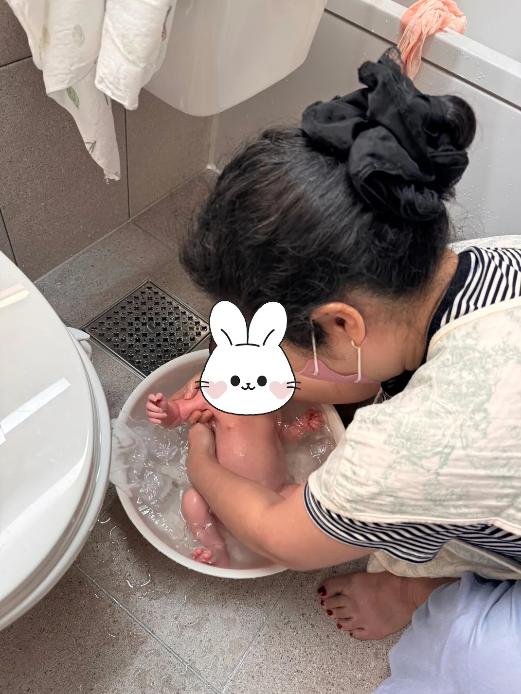 흰 대야에서 신생아를 목욕시키는 모습