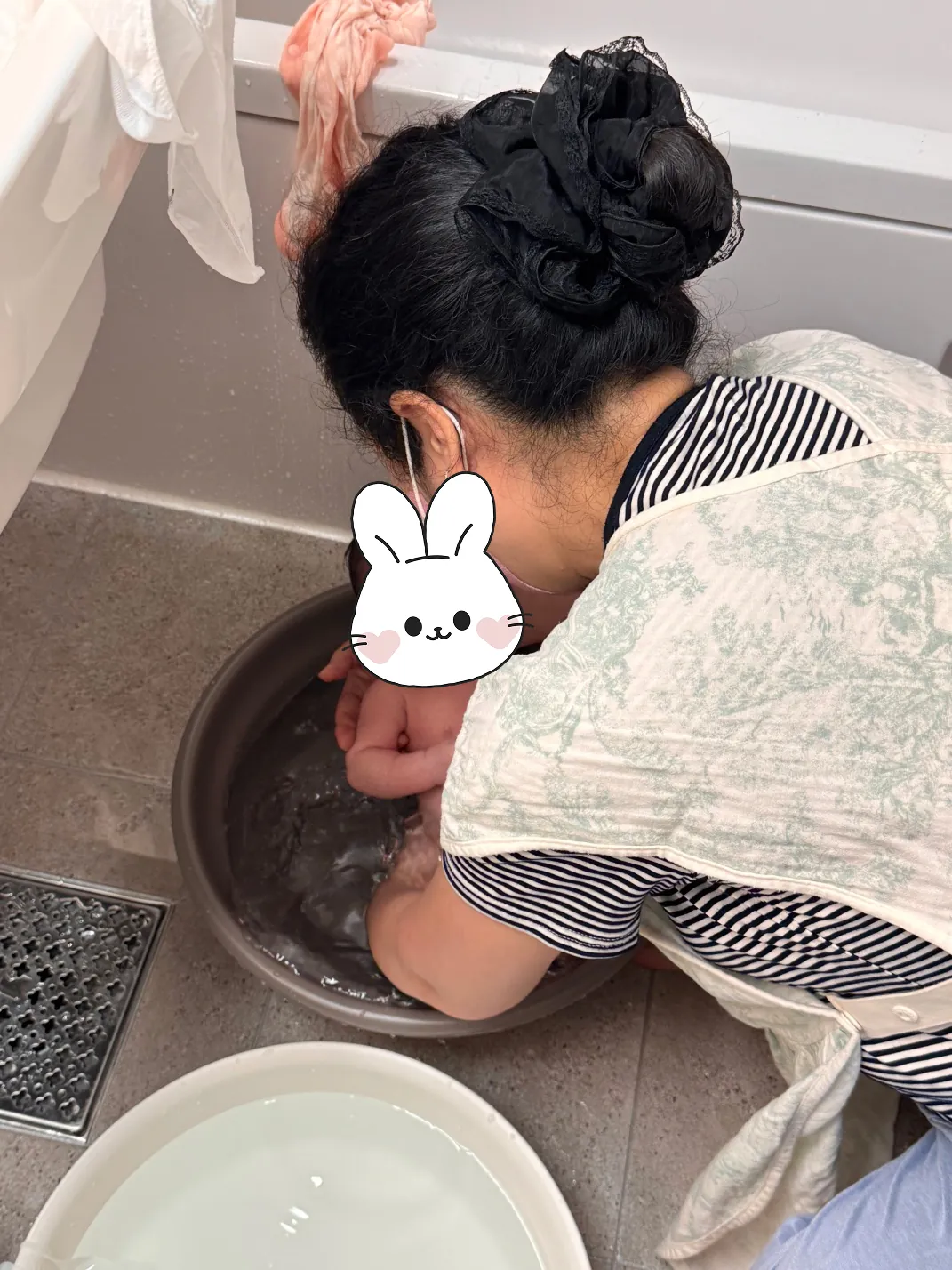 회색 대야에서 신생아를 목욕시키는 모습