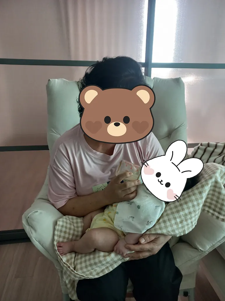 수유 쿠션에 기대 신생아를 품에 안고 있는 모습